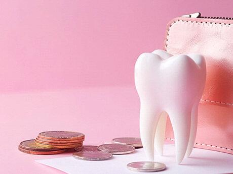 model tooth next to large coins and a coin purse with pink background