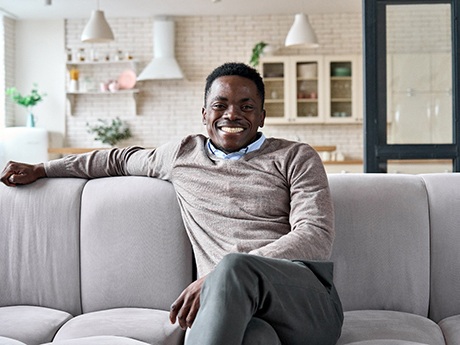 Man smiling while sitting on couch at home