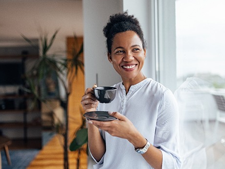 Woman smiling while drinking coffee at home