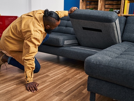 Man looking under couch cushion