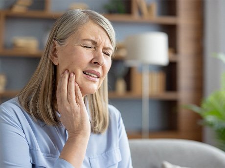 An older woman grimacing and suffering a toothache